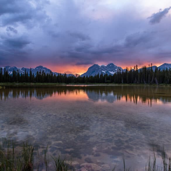 The sun sets over a pond in Spray Valley Provincal Park in Alberta, Canada.